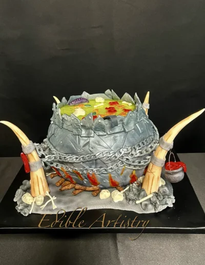 Fantasy cauldron cake with chains, horns, and themed edible decorations