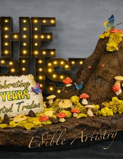 Custom sculpted celebration cake with detailed tree stump design and edible decorative elements