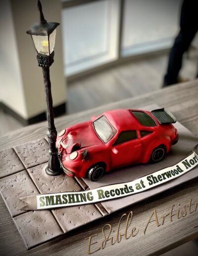 Custom red sports car cake with streetlight and crash scene detailing